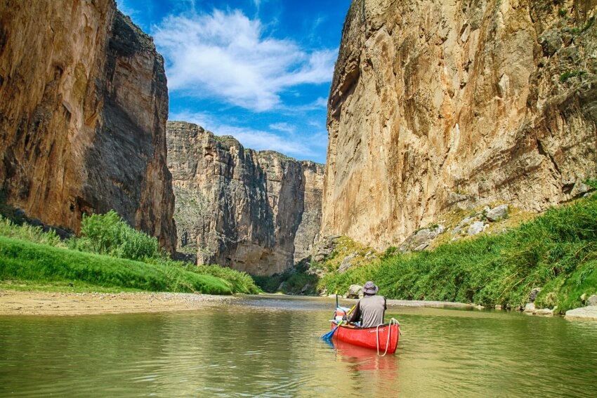 Man Canoeing on a River Between Rock Formations