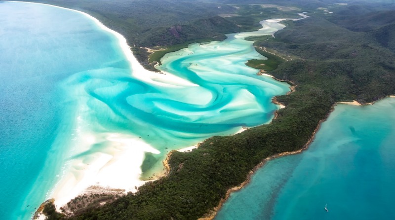 A beautiful aerial view of turquoise waters, white sandy beaches and green forests in the paradise of the Whitsunday's islands, Australia