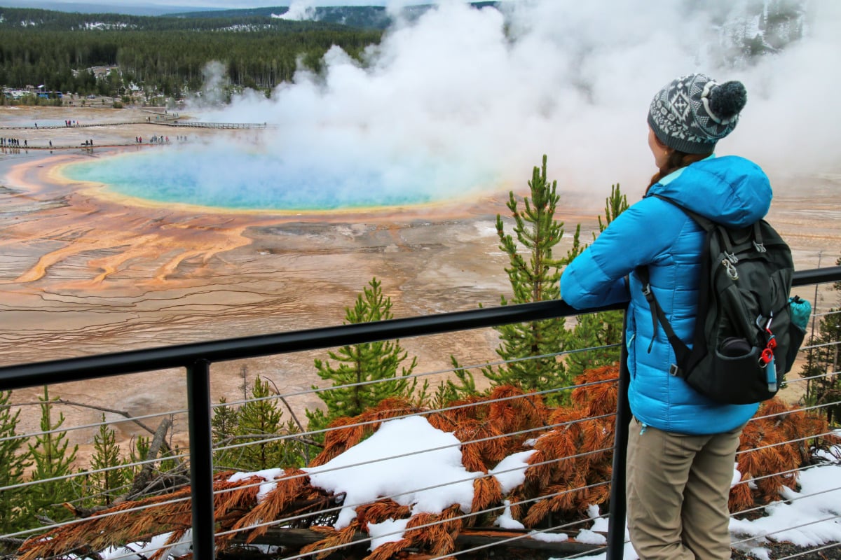 Tourist enjoying the view of Grand Prismatic Spring in Midway Geyser Basin, Yellowstone National Park, Wyoming, USA