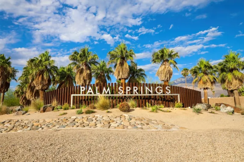 Welcome sign with palm trees and blue sky in the background in Palm Springs, California